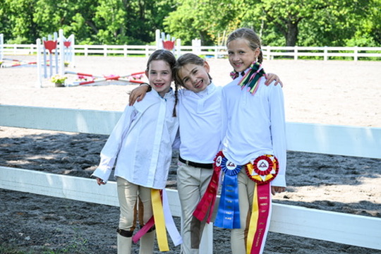 Three young riders together with their horse-show ribbons